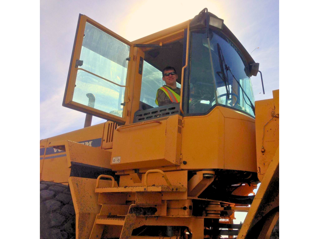 man wearing sunglasses and safety vest inside a volvo loader